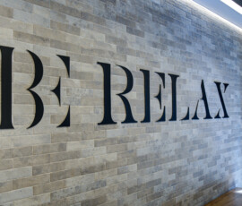 Interior wall with gray stone tiles and oversized black letters forming part of a sign in a modern lobby