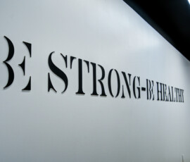 Close-up of large black letters on a white wall in a modern interior, with only part of a slogan visible from an angled perspective.
