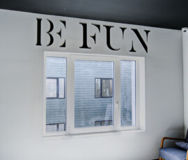Interior room with a white-framed window and a large decorative cut-out word above it on the wall; letters appear bold and serifed, spelling something like 'RENT'.